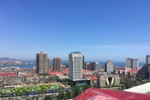 Une vue urbaine avec de hauts immeubles, un ciel dégagé et une étendue d’eau visible au loin.