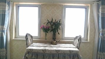 A dining table with a floral tablecloth, two chairs, and a vase with flowers.
