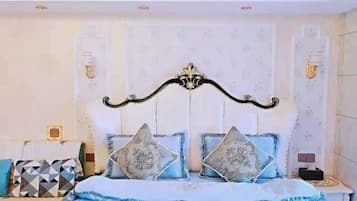 A bedroom with a bed, decorative pillows, a nightstand, and wall sconces.