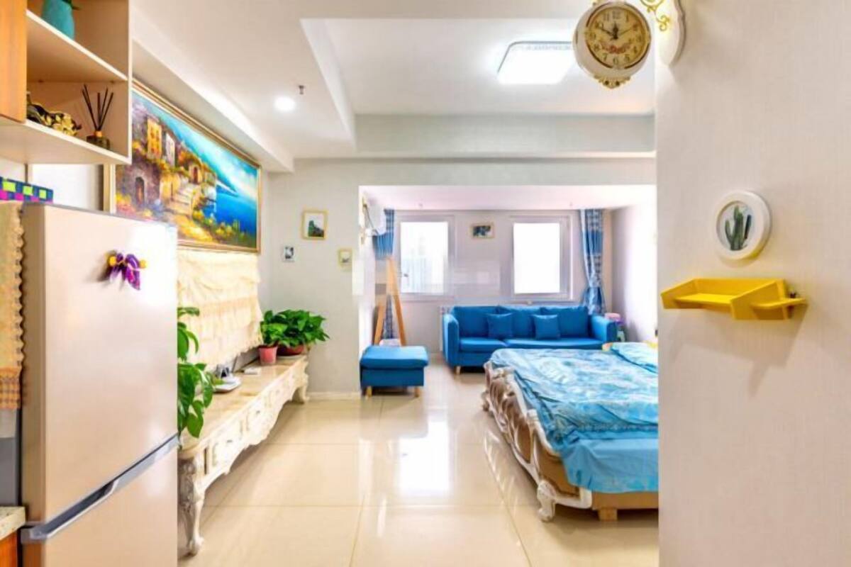 Una habitación de hotel moderna con cama, sofá, mesa de comedor y zona de cocina.