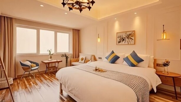 Ein Hotelzimmer mit einem großen Bett, einem Schreibtisch, einem Sessel, einem kleinen Tisch und einem Fenster.