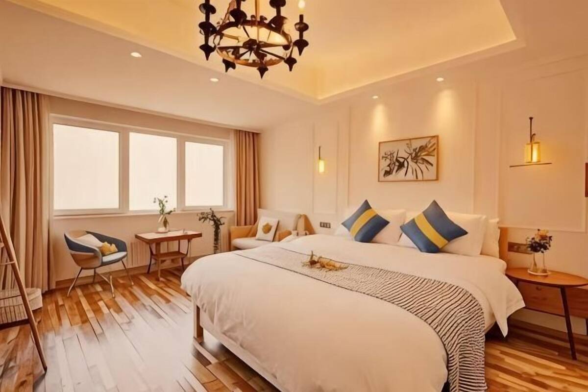 Una habitación de hotel con una cama grande, un escritorio, una silla, una mesita y una ventana.