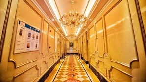 Ein Hotelkorridor mit Schachbrettboden, Kronleuchtern und einem Schild an der Wand.