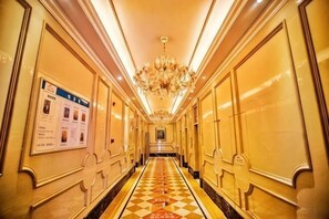 Un pasillo de hotel con piso de cuadros, candelabros y un cartel en la pared.