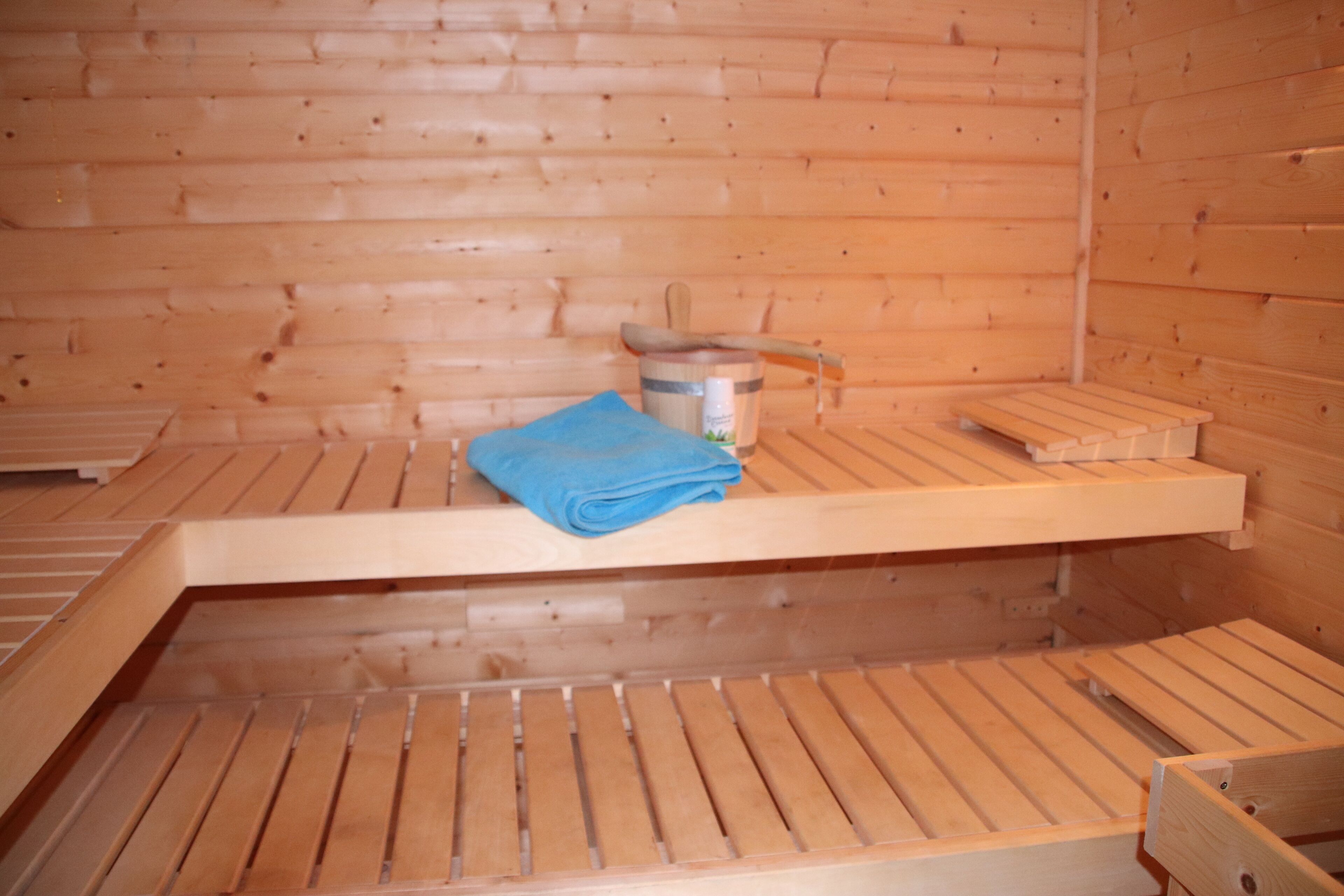 Un sauna avec des bancs en bois et une serviette bleue.