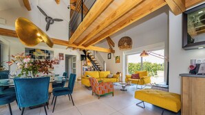 A spacious living area with a staircase, yellow sofas, blue chairs, and a dining table with chairs. - Trufièra, a lovely holiday house (Florimont-Gaumier)