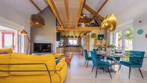 A modern living room with a yellow sofa, teal chairs, and a dining table. - Trufièra, a lovely holiday house (Florimont-Gaumier)