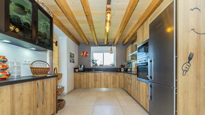 A modern kitchen with wooden cabinets, stainless steel appliances, and a tiled floor. - Trufièra, a lovely holiday house (Florimont-Gaumier)