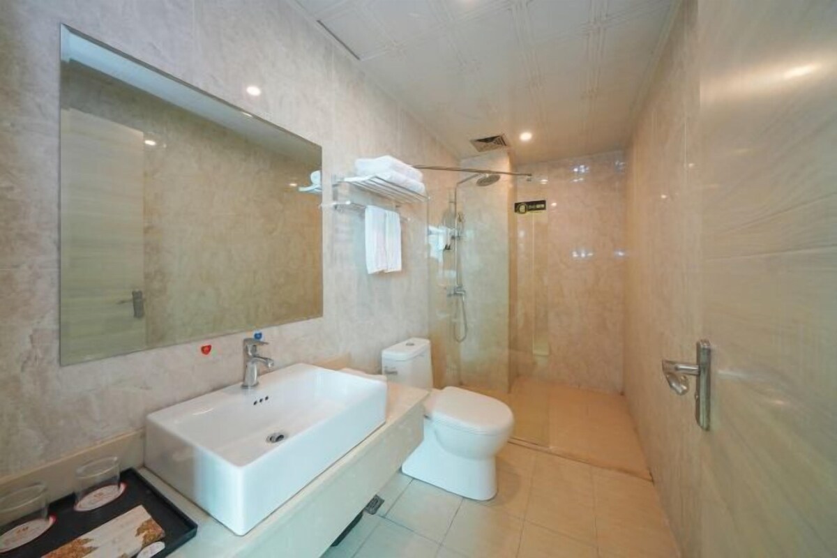 A modern bathroom with a large mirror, a sink, a toilet, and a glass-enclosed shower.