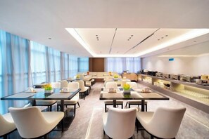 Una sala conferenze moderna in un hotel, con tavoli, sedie e un angolo cottura.