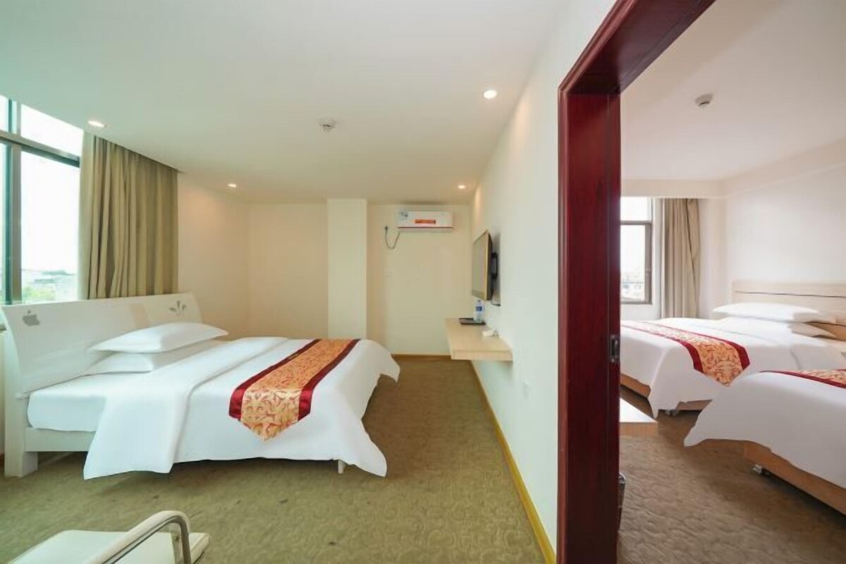 A hotel room with two beds, a TV, and a window with curtains.