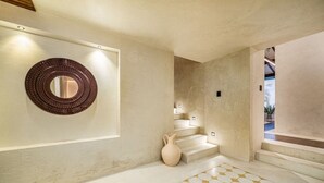 Een moderne badkamer met een grote spiegel, een decoratieve vaas en een vloer met een geometrisch patroon.