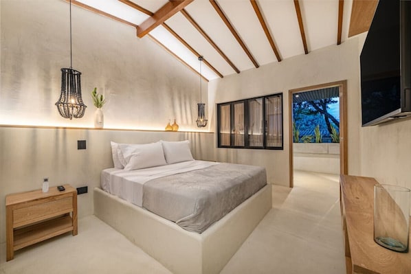 Une chambre moderne avec un grand lit, des tables de chevet et un téléviseur fixé au mur.
