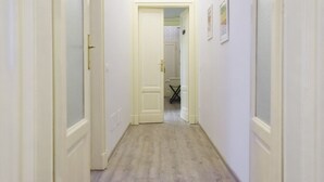 Un couloir étroit avec des portes blanches et un plancher de couleur claire.