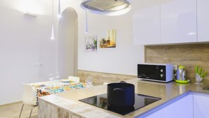 Une cuisine moderne avec des meubles blancs, un four à micro-ondes, une bouilloire et un coin repas avec une table dressée pour deux personnes.