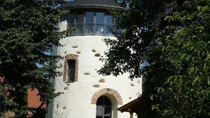 Une tour blanche dotée d’un balcon, de fenêtres en arc de cercle et d’une entrée en briques.