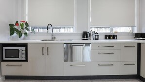 A modern kitchen with white cabinets, a built-in microwave, a dishwasher, and a coffee maker.