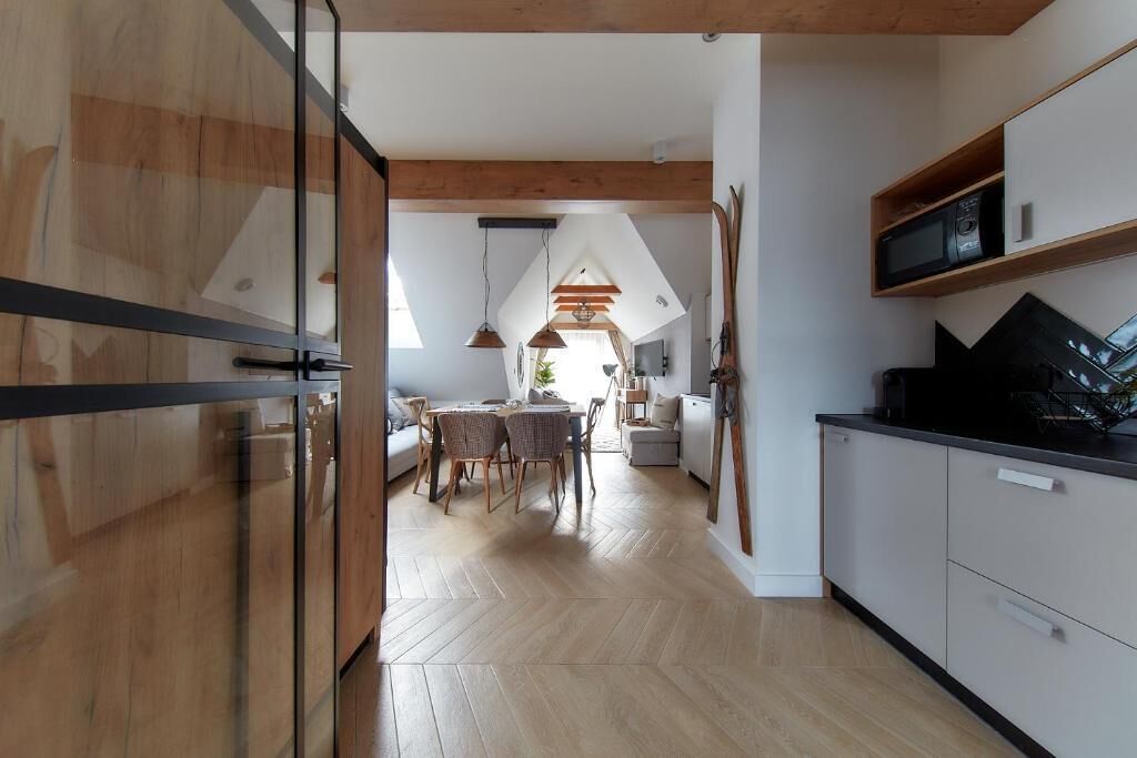 Eine moderne Küche mit Holzboden, einem Essbereich mit Fischgrätmuster und einer sichtbaren Kücheninsel.