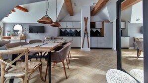 Une cuisine moderne avec des meubles blancs, une table à manger en bois et un parquet à motifs en chevrons.
