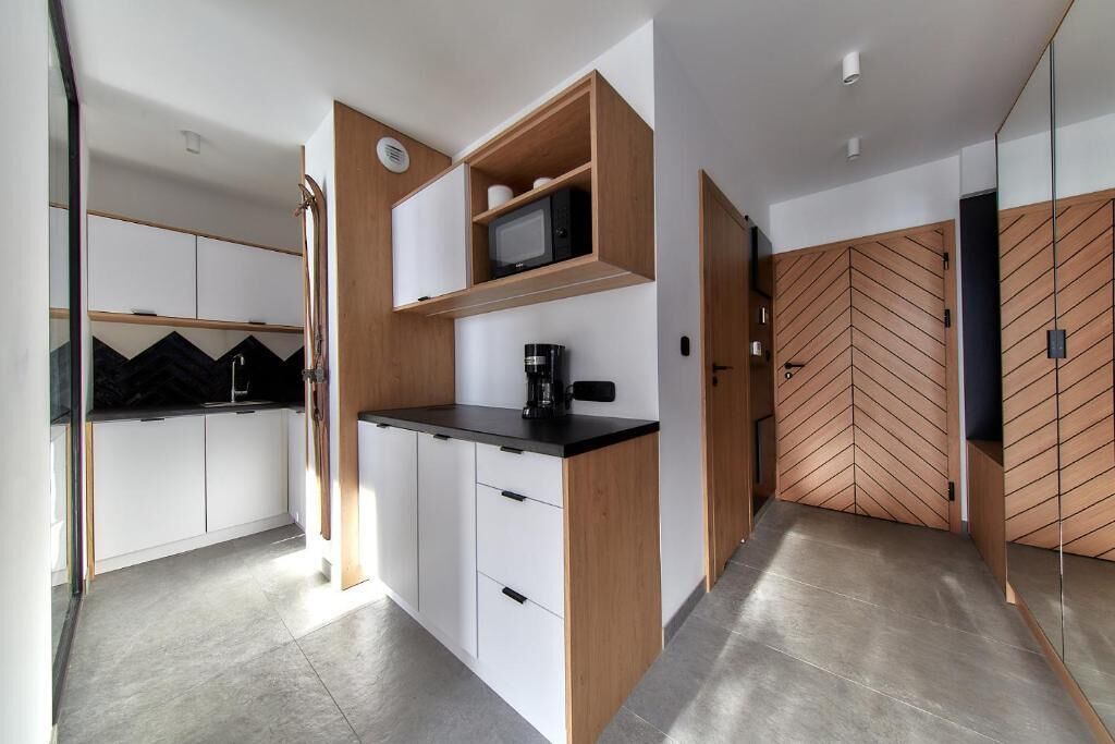 Eine moderne Küche mit weißen Schränken, einer schwarzen Arbeitsplatte und Holzregalen.