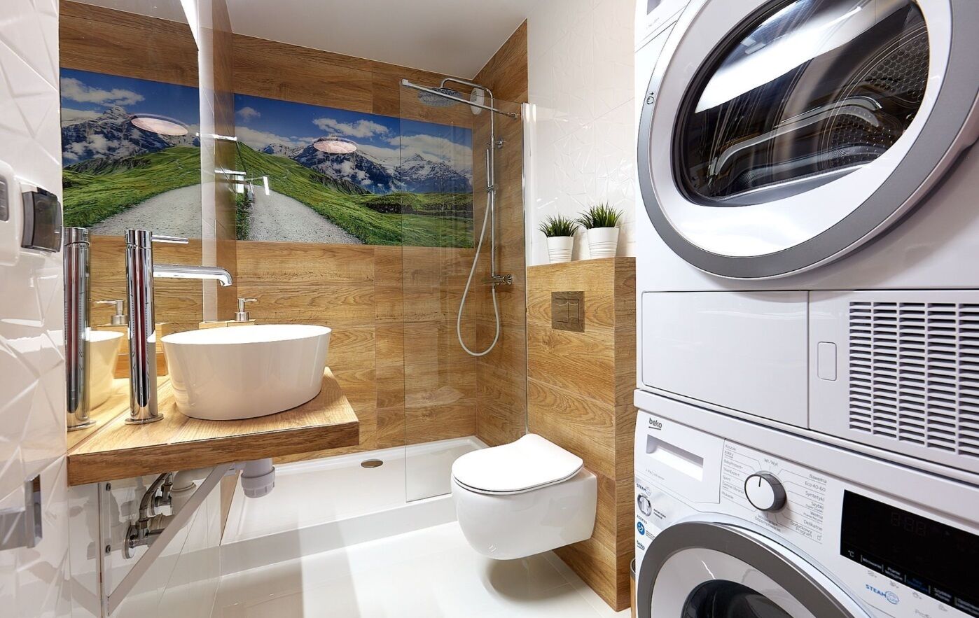 A modern bathroom with a wooden vanity, a large sink, a toilet, a shower, and a built-in washing machine.