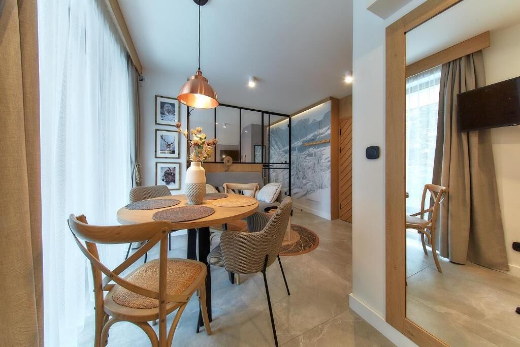 A dining area with a round table, wicker chairs, and a pendant light.