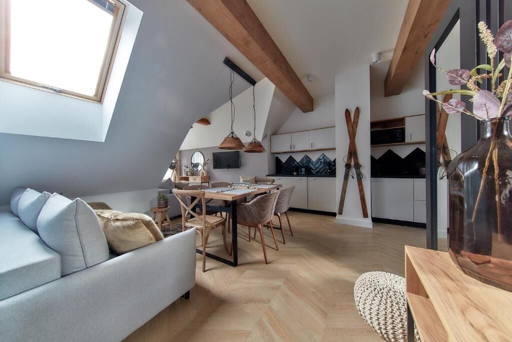 A modern loft apartment with a dining area, kitchen, and a large window.