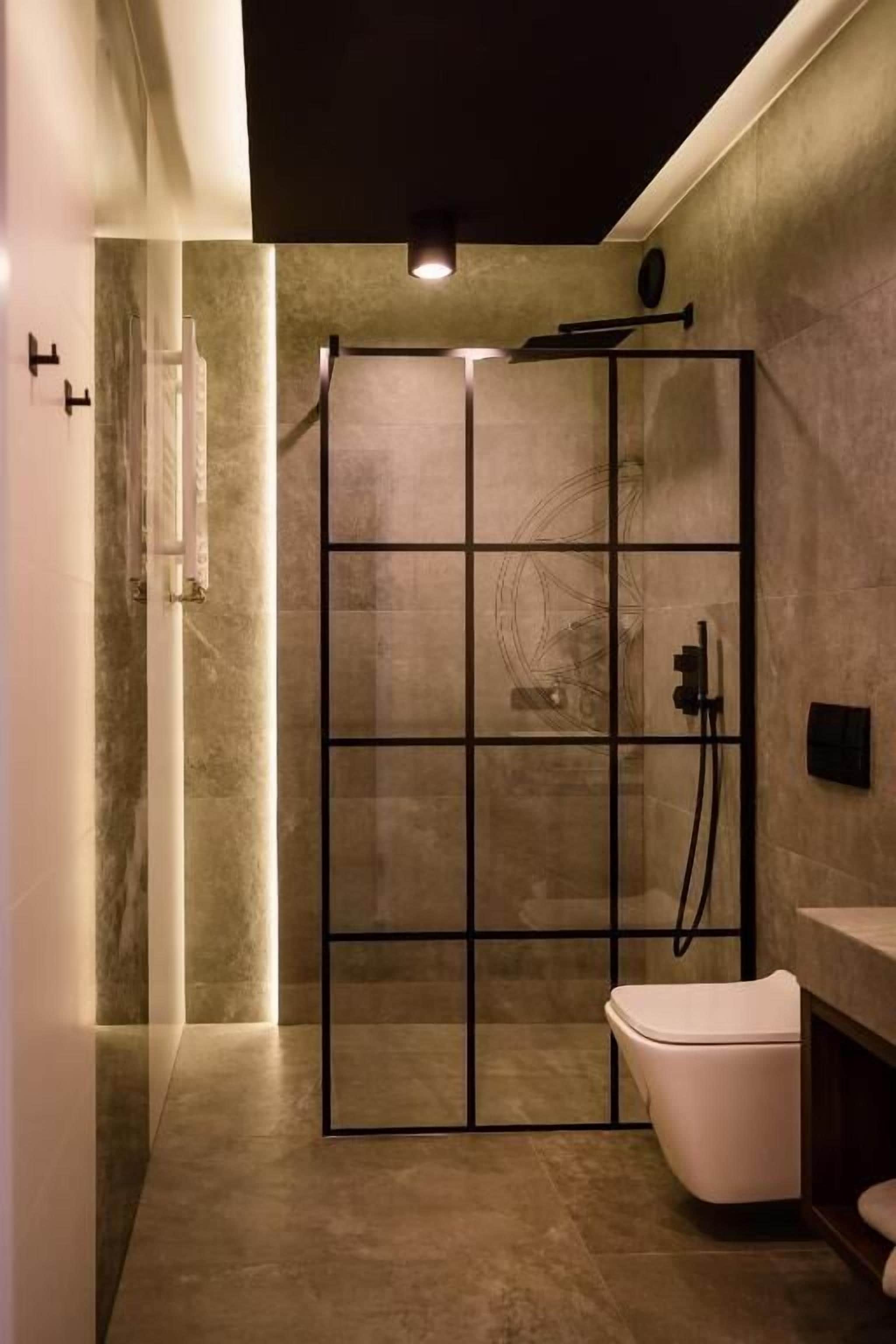 Ein modernes Badezimmer mit Duschkabine aus Glas, einer weißen Toilette und einer dunklen Arbeitsplatte.