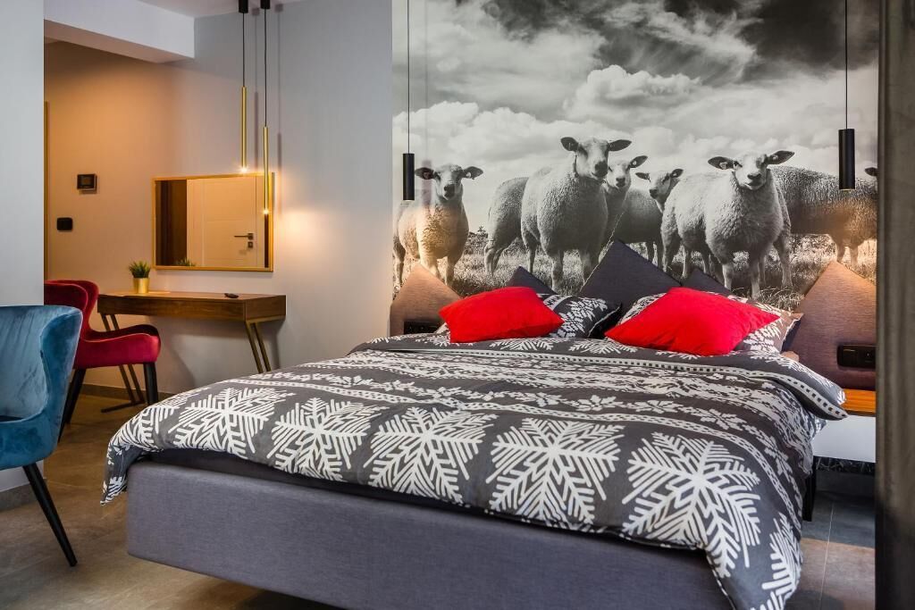 A modern bedroom with a large bed, a desk, and a chair.