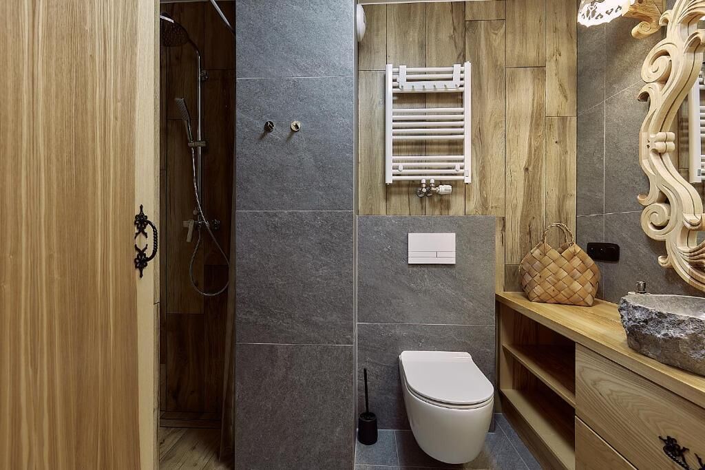 Een moderne badkamer met douche, toilet en wastafel.