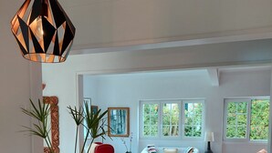 Un'ampia zona giorno con tavolo da pranzo in legno, sedie rosse e una lampada a sospensione moderna.