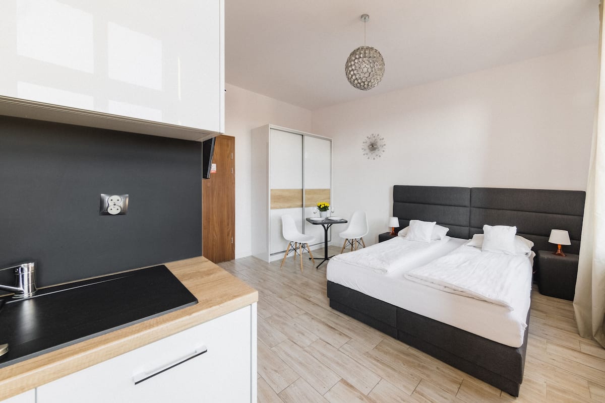 A modern hotel room with a large bed, a small desk, a chair, a mirror, and a decorative wall piece.