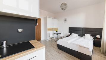 A modern hotel room with a large bed, a small desk, a chair, a mirror, and a decorative wall piece.