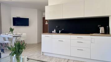 A modern kitchen with white cabinets, a black countertop, and a glass coffee table.