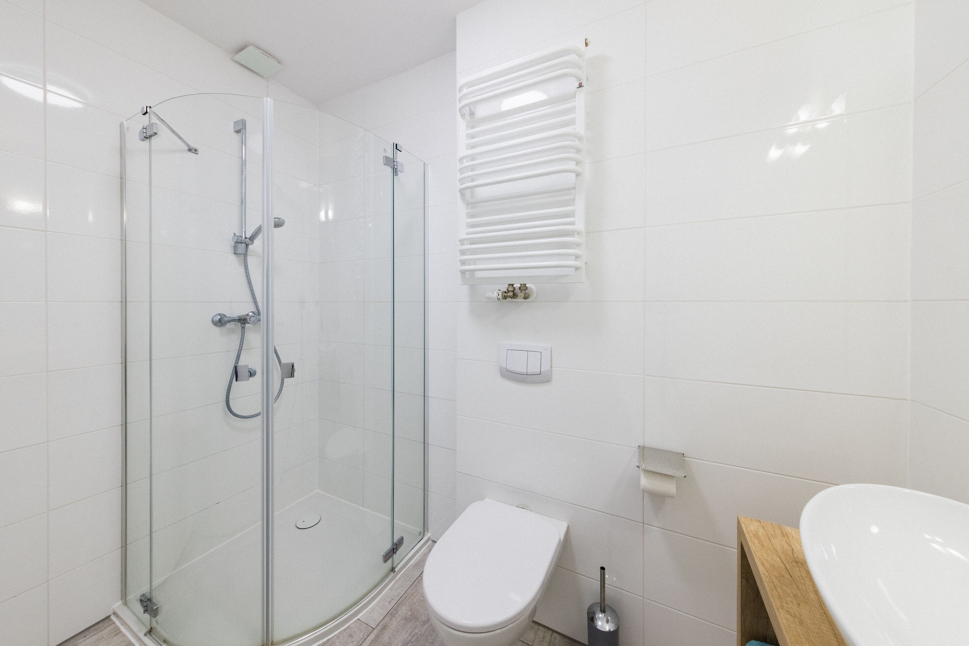 A modern bathroom with a glass-enclosed shower, a white toilet, and a wooden vanity with a sink.