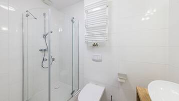 A modern bathroom with a glass-enclosed shower, a white toilet, and a wooden vanity with a sink.