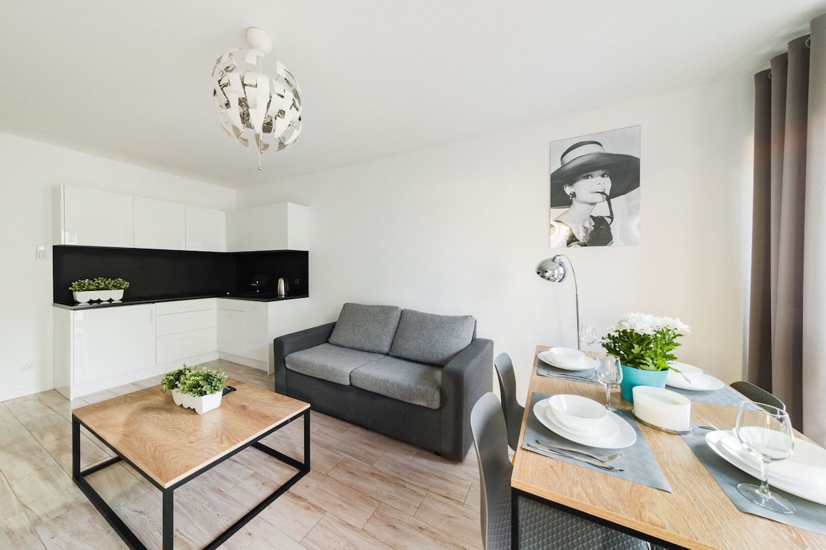 A modern living room with a sofa, dining table, and kitchen area.