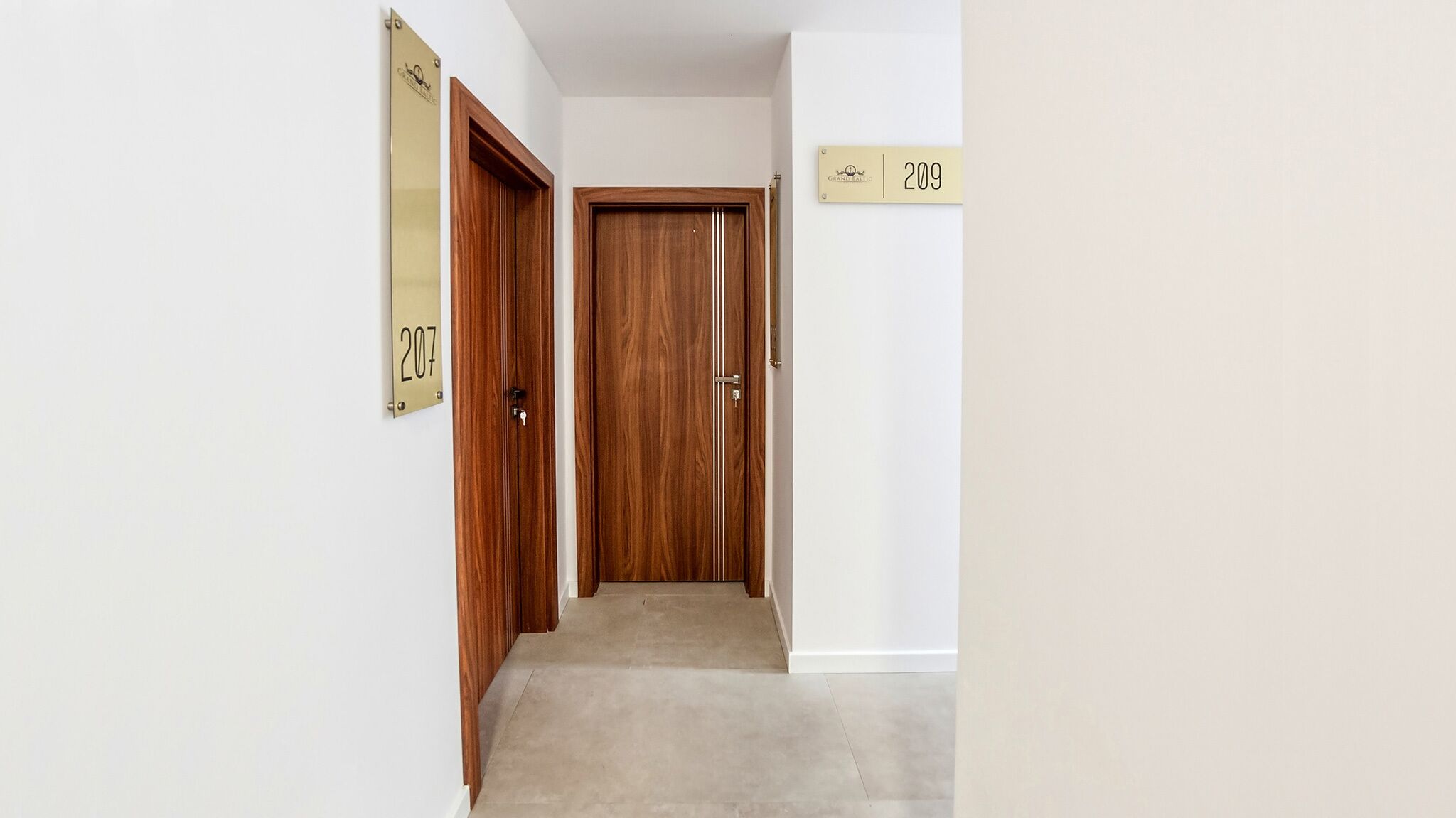 Un pasillo con puertas de madera, letreros numerados y piso alfombrado.