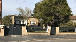 Un conjunto residencial cerrado con una casa, un árbol grande y un cielo despejado.