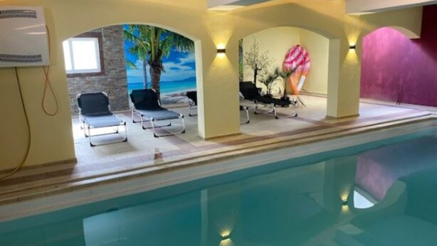 Una piscina interior con sillas de descanso y un mural de una escena de playa.