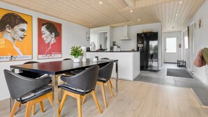A modern kitchen with a central island, wooden ceiling, and a dining area with black chairs and a wooden table. - 3 bedroom stunning home in Hejls (Hejls)