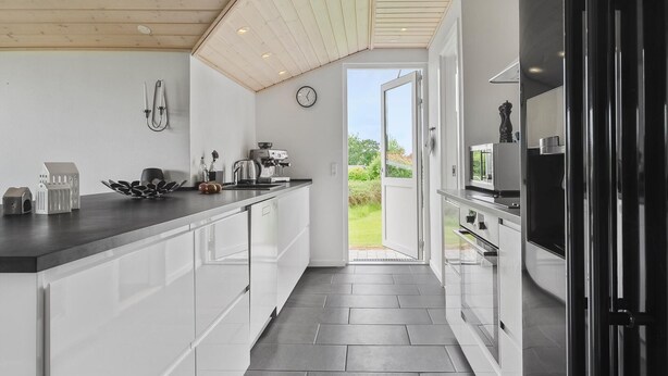 A modern kitchen with white cabinetry, a coffee machine, and a view to the outdoors. - 3 bedroom stunning home in Hejls (Hejls)