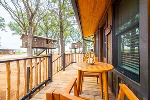 A wooden deck with a round table and benches, surrounded by trees and wooden cabins. - The Nuthatch Cabin 15 MIN to Magnolia Baylor (Elm Mott)