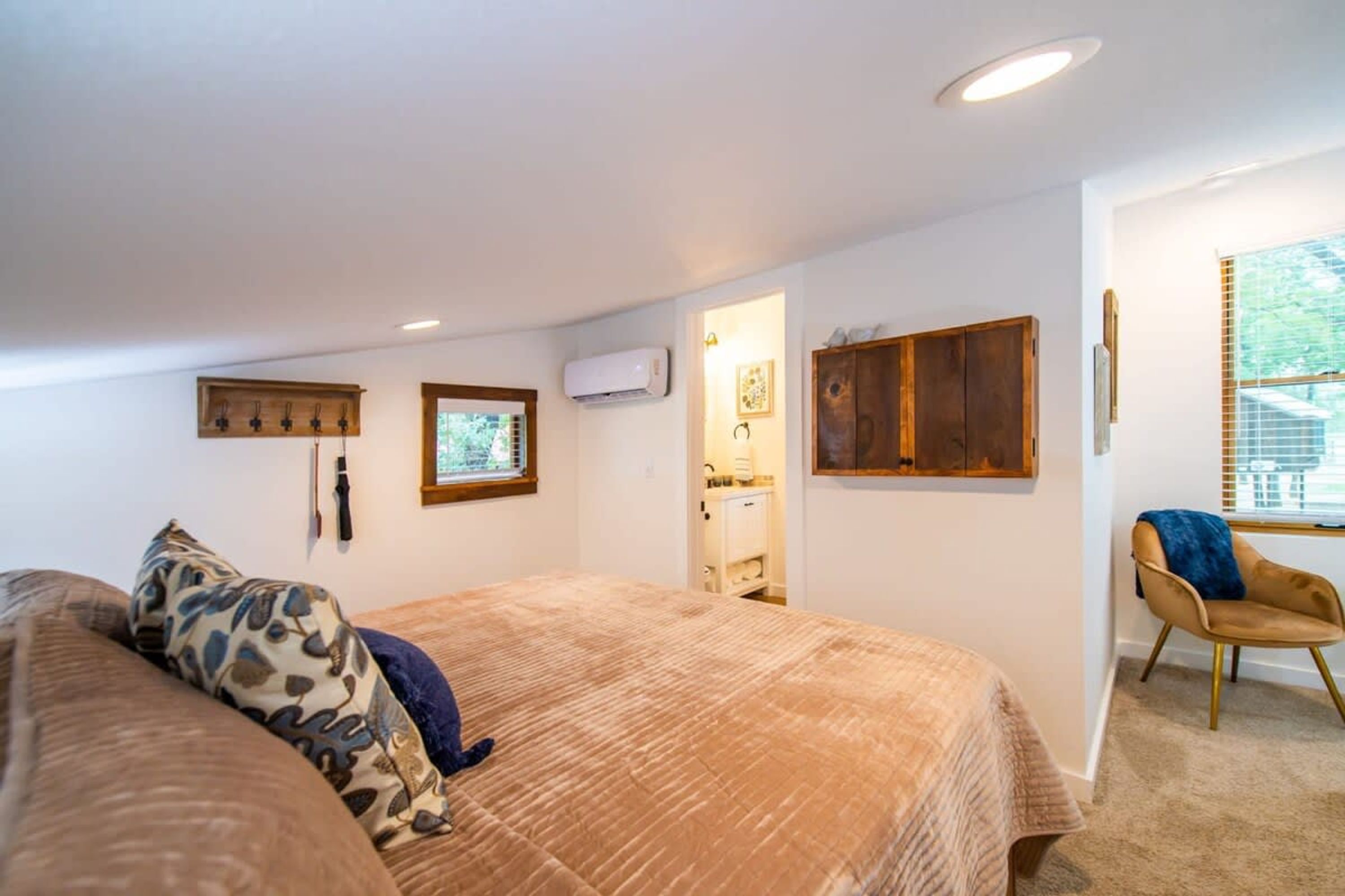 A bedroom with a large bed, a chair, a wardrobe, and a window with blinds.