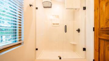 A glass-enclosed shower with a towel rack and a soap dispenser.