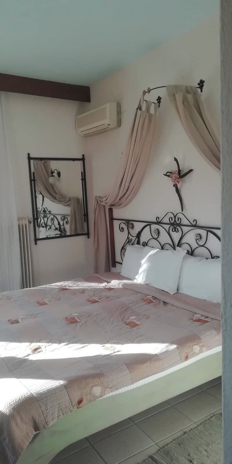 A bedroom with a bed, a mirror, an air conditioning unit, and a decorative wall piece.