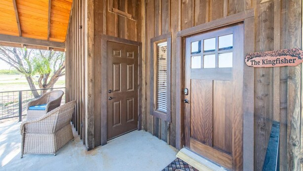 Entrada a una cabaña de madera con un letrero que dice "The Kingfisher".