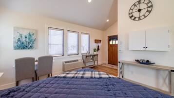 A bedroom with a bed, a desk, a chair, a clock, and a wardrobe.