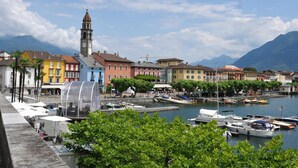 Une ville côtière aux bâtiments aux couleurs vives, avec un imposant beffroi et des bateaux amarrés le long de la rive.