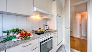 Une cuisine moderne avec des meubles blancs, un plan de travail en granit, une cuisinière et un four.